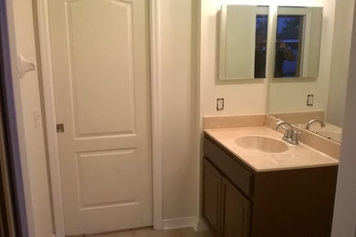 Modelo de cuarto de baño clásico grande con puertas de armario de madera en tonos medios, paredes blancas, suelo de baldosas de cerámica y encimera de granito