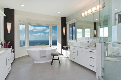 Inspiration for a large contemporary ensuite bathroom in Hawaii with flat-panel cabinets, white cabinets, a freestanding bath, a corner shower, a one-piece toilet, travertine tiles, white walls, porcelain flooring, a vessel sink, engineered stone worktops, grey floors and a hinged door.