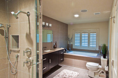 Foto de cuarto de baño actual con armarios con paneles lisos, puertas de armario de madera en tonos medios, bañera encastrada sin remate y baldosas y/o azulejos beige
