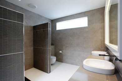 Aménagement d'une salle de bain contemporaine de taille moyenne avec une vasque, un plan de toilette en quartz modifié, une douche ouverte, WC suspendus, un carrelage marron et un mur marron.