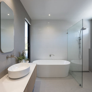 This is an example of a contemporary bathroom in Perth with light wood cabinets, a freestanding tub, an open shower, gray tile, porcelain tile, tile benchtops, white benchtops, a double vanity and a floating vanity.