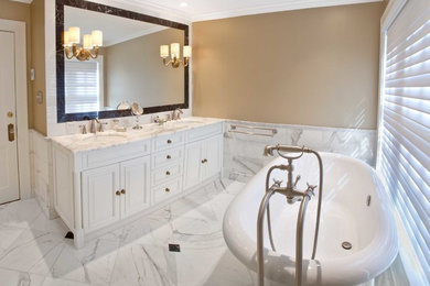 カンザスシティにあるラグジュアリーな広いトラディショナルスタイルのおしゃれなマスターバスルーム (レイズドパネル扉のキャビネット、白いキャビネット、置き型浴槽、シャワー付き浴槽	、分離型トイレ、白いタイル、白い壁、大理石の床、コンソール型シンク、大理石の洗面台) の写真