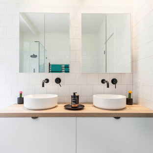 This is an example of a contemporary bathroom in Melbourne with flat-panel cabinets, white cabinets, a drop-in tub, white tile, a vessel sink, wood benchtops, brown benchtops and a double vanity.