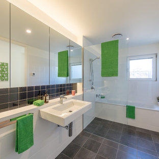 This is an example of a small contemporary master bathroom in Canberra - Queanbeyan with glass-front cabinets, an alcove tub, an open shower, white tile, ceramic tile, white walls, ceramic floors, a wall-mount sink and grey floor.
