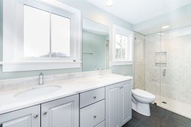 Corner shower - mid-sized transitional master gray tile and subway tile porcelain tile and gray floor corner shower idea in Other with raised-panel cabinets, gray cabinets, a two-piece toilet, green walls, an undermount sink, marble countertops and a hinged shower door