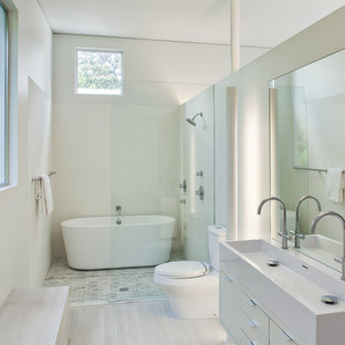 Inredning av ett modernt mellanstort en-suite badrum, med släta luckor, vita skåp, ett fristående badkar, en dusch/badkar-kombination, en toalettstol med separat cisternkåpa, flerfärgad kakel, cementkakel, vita väggar, bambugolv, ett väggmonterat handfat och bänkskiva i akrylsten