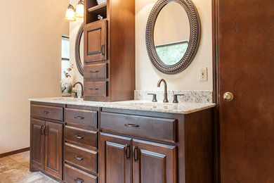 Example of a mid-sized mountain style master brown tile ceramic tile bathroom design in Oklahoma City with an undermount sink, raised-panel cabinets, dark wood cabinets, granite countertops, a two-piece toilet and beige walls