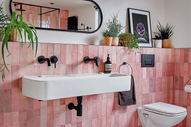 Example of a mid-sized trendy kids' pink tile and ceramic tile terrazzo floor, black floor and single-sink bathroom design in London with black cabinets, a wall-mount toilet, white walls, a trough sink and a niche