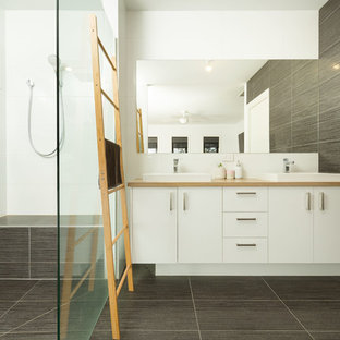 Contemporary bathroom in Other with flat-panel cabinets, white cabinets, gray tile, a drop-in sink, wood benchtops, grey floor and beige benchtops.