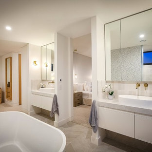 Design ideas for a contemporary master bathroom in Wollongong with raised-panel cabinets, white cabinets, a freestanding tub, gray tile, white walls, a vessel sink, grey floor and grey benchtops.