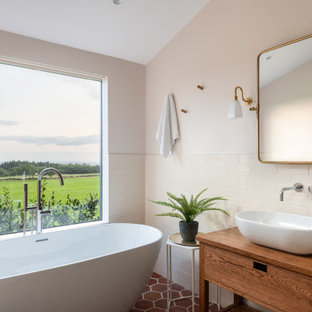 Mid-sized country bathroom in Other with furniture-like cabinets, brown cabinets, a freestanding tub, white tile, white walls, terra-cotta floors, wood benchtops, red floor, brown benchtops, subway tile and a vessel sink.