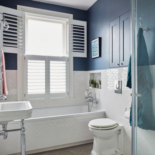 Inspiration for a small classic family bathroom in Kent with blue walls, grey floors, a built-in bath, a walk-in shower, a wall mounted toilet, white tiles, porcelain tiles, cement flooring, a hinged door, a single sink, a freestanding vanity unit and a console sink.