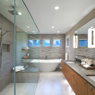 Large trendy master gray tile and porcelain tile porcelain tile and beige floor bathroom photo in Vancouver with flat-panel cabinets, medium tone wood cabinets, beige walls, an undermount sink, quartz countertops, a hinged shower door and gray countertops