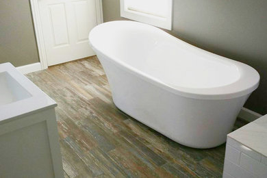 Imagen de cuarto de baño principal clásico de tamaño medio con puertas de armario blancas, bañera exenta, paredes beige, encimera de cuarcita y suelo marrón