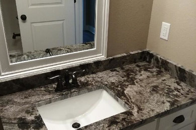Example of a bathroom design in Dallas with white cabinets, an undermount sink and granite countertops
