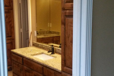 オースティンにある中くらいなトラディショナルスタイルのおしゃれなバスルーム (浴槽なし) (レイズドパネル扉のキャビネット、中間色木目調キャビネット、ベージュの壁、アンダーカウンター洗面器、ベージュの床) の写真