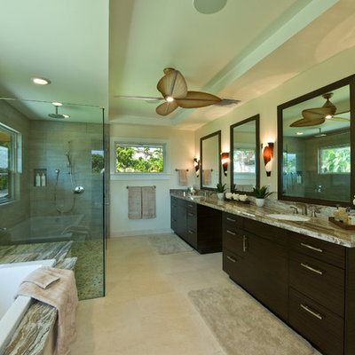 Inspiration for a large tropical master gray tile travertine floor and beige floor bathroom remodel in Hawaii with an undermount sink, flat-panel cabinets, dark wood cabinets, granite countertops, green walls and a hinged shower door
