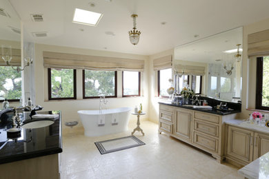 Photo of an expansive traditional ensuite bathroom in San Francisco with raised-panel cabinets, distressed cabinets, a freestanding bath, beige tiles, ceramic tiles, white walls, ceramic flooring, a submerged sink and granite worktops.