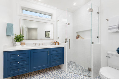 Corner shower - mid-sized country 3/4 white tile and ceramic tile ceramic tile and blue floor corner shower idea in San Francisco with blue cabinets, white walls, an undermount sink, quartz countertops, a hinged shower door, white countertops, recessed-panel cabinets and a two-piece toilet