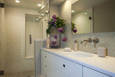 デンバーにある高級な小さなコンテンポラリースタイルのおしゃれなバスルーム (浴槽なし) (アンダーカウンター洗面器、フラットパネル扉のキャビネット、白いキャビネット、人工大理石カウンター、アルコーブ型シャワー、一体型トイレ	、白いタイル、セラミックタイル、グレーの壁、磁器タイルの床) の写真