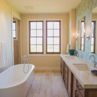 Esempio di una stanza da bagno tropicale con lavabo sottopiano, ante in legno bruno, vasca freestanding, piastrelle blu, piastrelle a mosaico, pareti beige e vasca/doccia