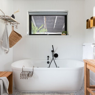 Medium sized scandinavian ensuite bathroom in Cornwall with light wood cabinets, a freestanding bath, white walls, ceramic flooring, wooden worktops, multi-coloured floors, beige worktops, open cabinets and a vessel sink.