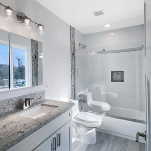 Example of a mid-sized trendy 3/4 gray tile and mosaic tile medium tone wood floor and gray floor bathroom design in Los Angeles with shaker cabinets, white cabinets, a one-piece toilet, white walls, an undermount sink and granite countertops