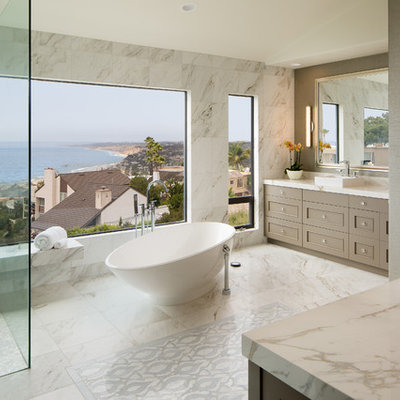 Inspiration for a large transitional master white tile white floor, marble floor, double-sink and wallpaper bathroom remodel in San Diego with a vessel sink, recessed-panel cabinets, brown cabinets, white countertops, a one-piece toilet, gray walls, marble countertops and a built-in vanity