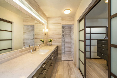 Example of a mid-sized trendy master beige tile and stone tile limestone floor and beige floor bathroom design in San Diego with an undermount sink, flat-panel cabinets, medium tone wood cabinets, quartz countertops and beige walls