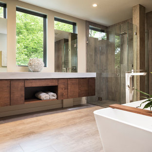 Modern inredning av ett litet en-suite badrum, med släta luckor, skåp i mellenmörkt trä, ett fristående badkar, en kantlös dusch, beige kakel, stenkakel, beige väggar, klinkergolv i keramik, ett integrerad handfat och bänkskiva i betong