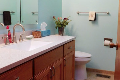 シアトルにあるお手頃価格の中くらいなコンテンポラリースタイルのおしゃれなバスルーム (浴槽なし) (レイズドパネル扉のキャビネット、中間色木目調キャビネット、アルコーブ型シャワー、一体型トイレ	、ベージュのタイル、磁器タイル、青い壁、磁器タイルの床、アンダーカウンター洗面器、クオーツストーンの洗面台) の写真