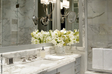 Immagine di una stanza da bagno contemporanea con lavabo sottopiano, ante con bugna sagomata, ante grigie, top in marmo, vasca da incasso e lastra di pietra