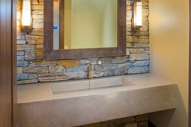 Ejemplo de cuarto de baño rústico con lavabo de seno grande, encimera de cemento y piedra