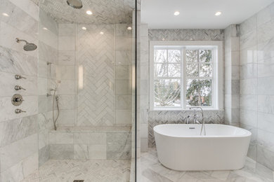 デトロイトにあるトランジショナルスタイルのおしゃれなマスターバスルーム (置き型浴槽、アルコーブ型シャワー、グレーのタイル、大理石タイル、大理石の床、グレーの床、開き戸のシャワー) の写真