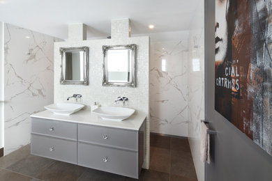 Cette photo montre une grande salle de bain principale moderne avec un placard à porte plane, des portes de placard grises, WC à poser, une vasque, un plan de toilette en surface solide et un sol gris.