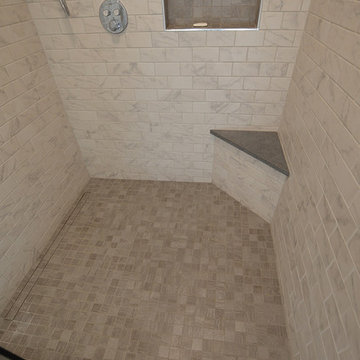 Large, walk-in shower with beige floor, marble-look walls