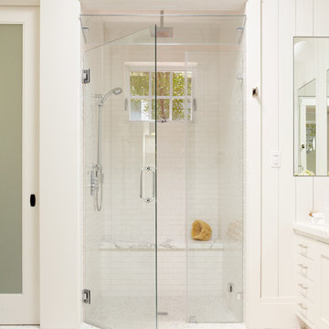 Large white tile shower with bench, steam shower, and window for natural light