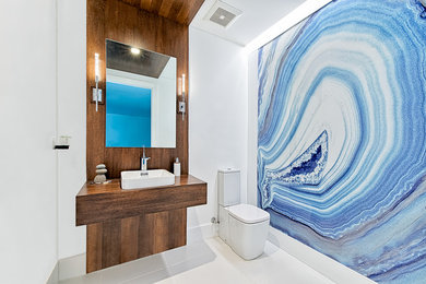 Mittelgroßes Modernes Duschbad mit Wandtoilette mit Spülkasten, Aufsatzwaschbecken, Waschtisch aus Holz, blauer Wandfarbe, offenen Schränken, hellbraunen Holzschränken und Porzellan-Bodenfliesen in Miami