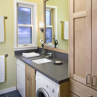 This is an example of a country bathroom in San Francisco with light wood cabinets, slate floors, yellow walls, black floor and a laundry.