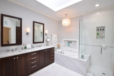 Mid-sized elegant white tile and porcelain tile porcelain tile and white floor corner shower photo in Dallas with shaker cabinets, brown cabinets, an undermount tub, a one-piece toilet, white walls, an undermount sink, marble countertops, a hinged shower door and white countertops