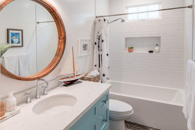 Example of a mid-sized beach style white tile and ceramic tile cement tile floor and black floor bathroom design in San Diego with shaker cabinets, blue cabinets, a one-piece toilet, white walls, an undermount sink, quartzite countertops and white countertops