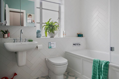 ハンプシャーにあるお手頃価格の中くらいなトランジショナルスタイルのおしゃれな子供用バスルーム (ドロップイン型浴槽、シャワー付き浴槽	、一体型トイレ	、白いタイル、セラミックタイル、クッションフロア、壁付け型シンク、緑の床) の写真