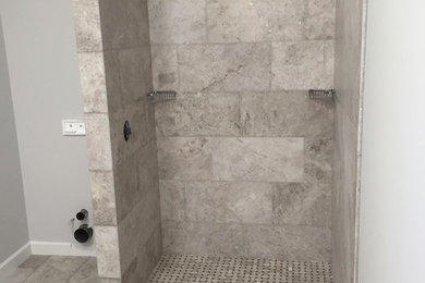 Modelo de cuarto de baño principal moderno con ducha esquinera, suelo de piedra caliza, suelo gris y ducha con puerta con bisagras