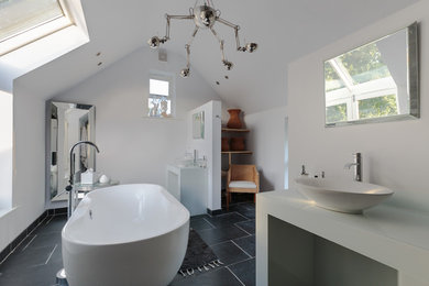 This is an example of a large contemporary ensuite bathroom in Other with open cabinets, white cabinets, a freestanding bath, white walls, a vessel sink, black floors and white worktops.