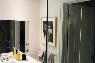 Small modern shower room bathroom in Montreal with grey cabinets, a built-in shower, a one-piece toilet, grey tiles, porcelain tiles, white walls, marble flooring, an integrated sink, engineered stone worktops, white floors, a hinged door and white worktops.