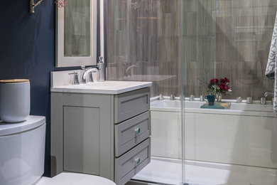 Small modern ensuite wet room bathroom in Providence with shaker cabinets, grey cabinets, an alcove bath, a two-piece toilet, grey tiles, blue walls, dark hardwood flooring, a submerged sink, engineered stone worktops and a sliding door.