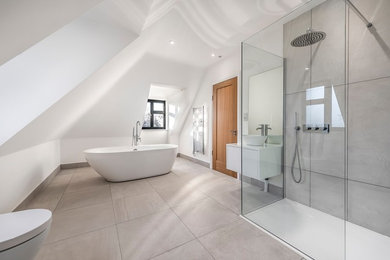 ロンドンにあるコンテンポラリースタイルのおしゃれなマスターバスルーム (フラットパネル扉のキャビネット、白いキャビネット、置き型浴槽、白い壁、ベッセル式洗面器、ベージュの床、白い洗面カウンター) の写真