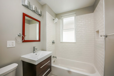 シカゴにある低価格の中くらいなコンテンポラリースタイルのおしゃれな浴室 (フラットパネル扉のキャビネット、濃色木目調キャビネット、ドロップイン型浴槽、一体型トイレ	、白いタイル、セラミックタイル、グレーの壁、セラミックタイルの床、一体型シンク、グレーの床) の写真