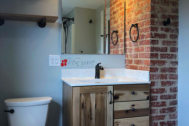 Small mountain style vinyl floor bathroom photo with shaker cabinets, medium tone wood cabinets, a two-piece toilet, blue walls, an integrated sink and white countertops
