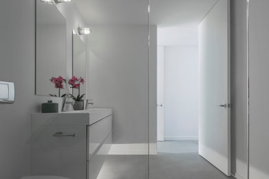 Medium sized modern ensuite bathroom in Phoenix with flat-panel cabinets, white cabinets, a wall mounted toilet, white tiles, white walls, concrete flooring and marble worktops.